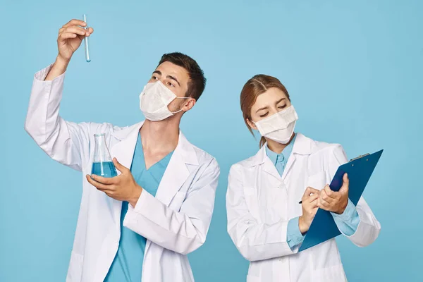 Stodio shot of young doctors in face masks  with test tubes