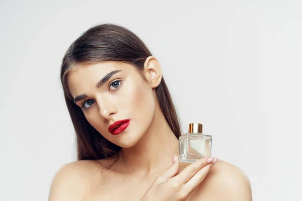 Portrait of young beautiful  woman with perfume bottle isolated on white background