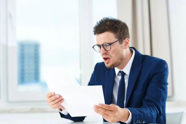 Young  angry businessman working in the office  with documents