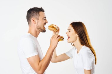 Hamburger yiyen genç ve güzel bir çift. Stüdyo çekimi