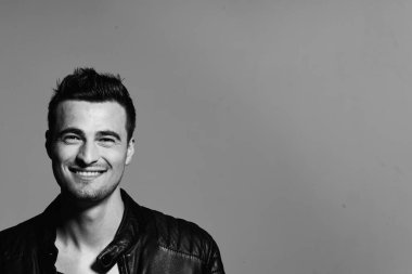 Stüdyoda poz veren siyah deri ceketli mutlu genç adamın portresi. Siyah ve beyaz  