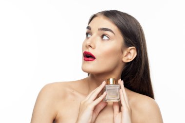 Beyaz arka planda izole edilmiş parfüm şişesiyle şaşırmış güzel bir kadının portresi.