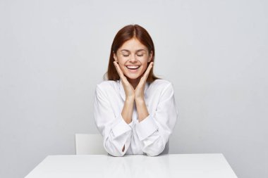 Genç, güzel, mutlu iş kadını ofiste oturuyor. 