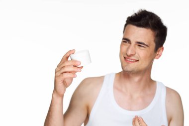 Stüdyo. Genç yakışıklı adam krem tutuyor. 