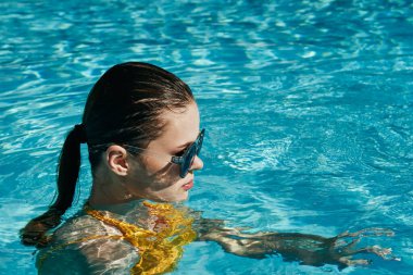 Genç ve güzel bir kadın havuzda dinleniyor.  