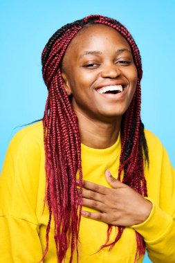 Mavi arka planda tek başına gülen genç bir kadın 