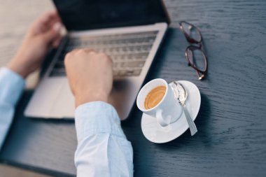 Kafede dizüstü bilgisayarla çalışan yakışıklı bir iş adamı.