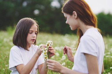 Genç anne ve kızı papatya tarlasında eğleniyorlar.