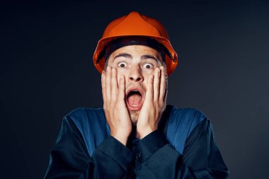 Stüdyo çekimi. Turuncu kasklı genç işçi şok oldu. 