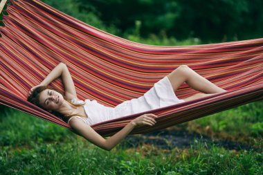 Genç ve güzel bir kadın hamakta dinleniyor.