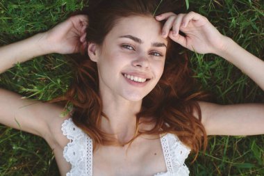 Genç bir kadın çimlerin üzerinde yatıyor. Üst görünüm