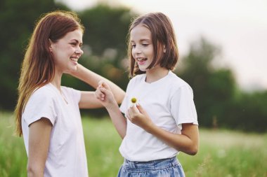 Genç anne ve kızı papatya tarlasında eğleniyorlar.