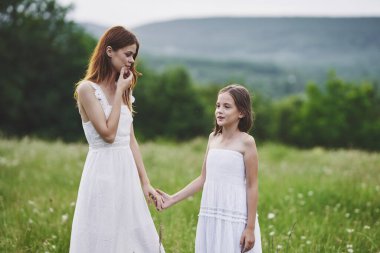 Genç anne ve kızı papatya tarlasında eğleniyorlar.