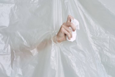 Plastik ve polietilen yırtıklar olan bir kadın eli.