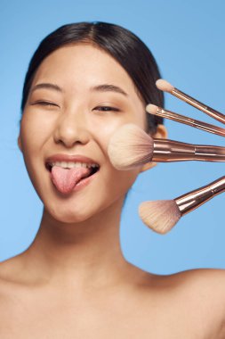 Stüdyo çekimi. Makyaj fırçalı genç Asyalı kadın.  