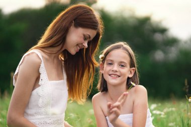 Genç anne ve kızı papatya tarlasında eğleniyorlar.