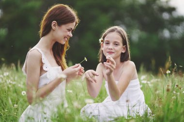 Genç anne ve kızı papatya tarlasında eğleniyorlar.