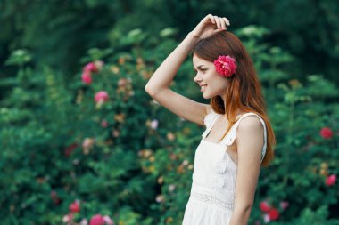 Bahçesinde gül çiçeği olan genç bir kadın
