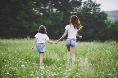 Genç anne ve kızı papatya tarlasında eğleniyorlar.