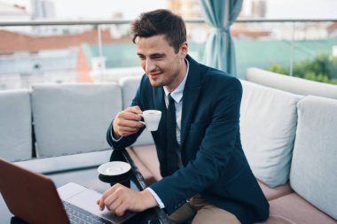 Kafede dizüstü bilgisayarı olan genç ve yakışıklı bir iş adamı. 