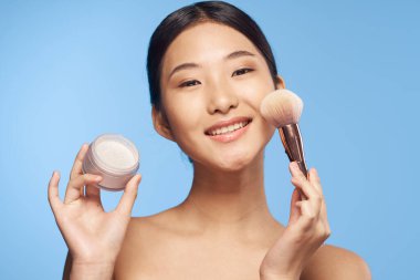 Pudra fırçalı genç Asyalı kadın. 