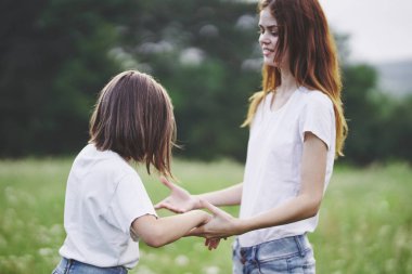 Genç anne ve kızı papatya tarlasında eğleniyorlar.