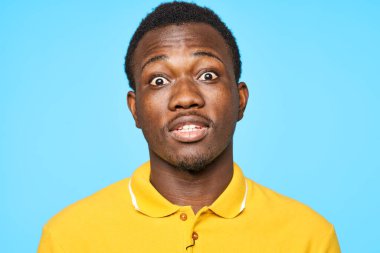 Stüdyoda poz veren yakışıklı genç adam mavi arka planda izole edilmiş.