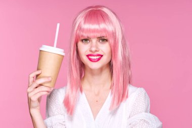 Kahve fincanıyla poz veren pembe peruklu güzel bir kadın.