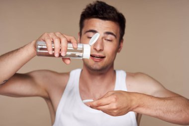 Stüdyo çekimi. Genç yakışıklı adam süngere losyon döküyor. 