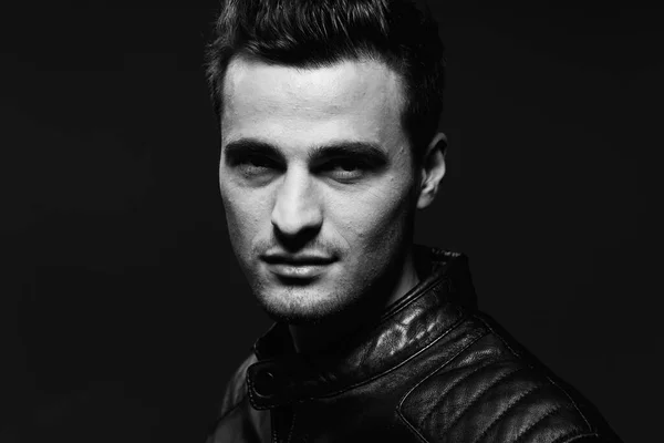 Young handsome man in leather jacket posing in studio. Black and white