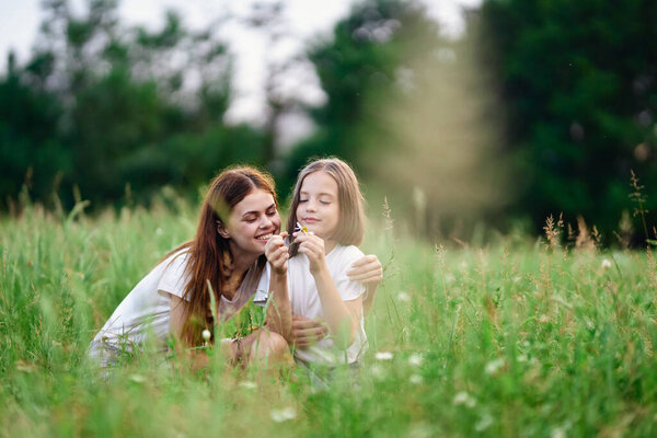 Young mother and her daughter having fun on camomile field