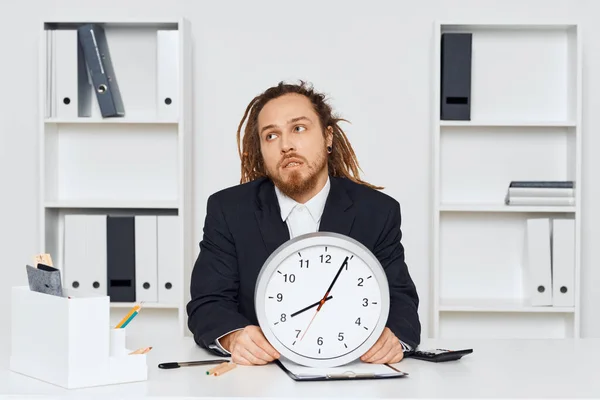 Young businessman sitting in the office with big clock