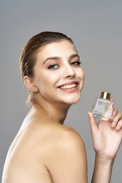 portrait of young beautiful woman with perfume bottle.  Studio shot.