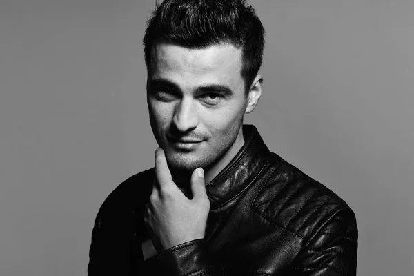 Young handsome man in leather jacket posing in studio. Black and white