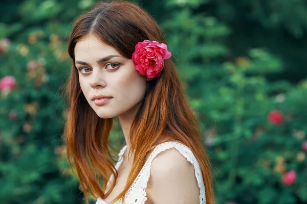 庭にバラの花を持つ若い女性 — ストック写真