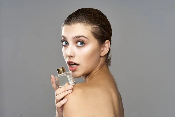 portrait of young beautiful woman with perfume bottle.  Studio shot.