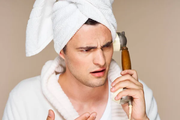 Young man in bathrobe talking on vintage phone. Studio shot. Isolated