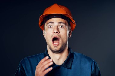Stüdyo çekimi. Turuncu kasklı genç işçi şok oldu.