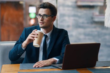 Kafede dizüstü bilgisayarla çalışan yakışıklı bir iş adamı.