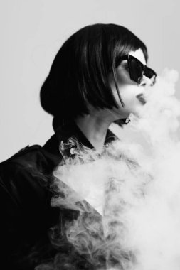 Stüdyoda sigara içen güneş gözlüklü güzel bir kadın. Moda fotoğrafçılığı 