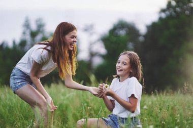 Genç anne ve kızı papatya tarlasında eğleniyorlar.