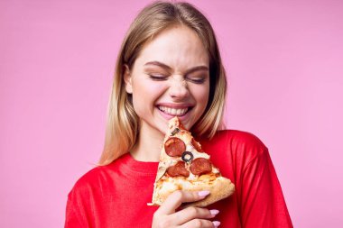 Güzel, mutlu bir kadın arka planda pizza yiyor. 