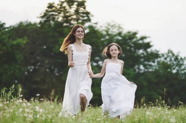 Genç anne ve kızı papatya tarlasında eğleniyorlar.