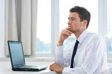 Genç yakışıklı iş adamı ofiste düşünüyor. 