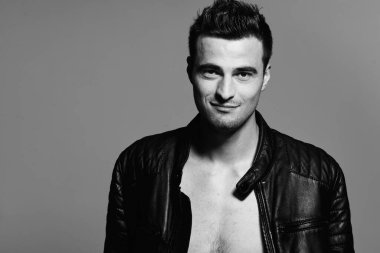 Stüdyoda poz veren deri ceketli yakışıklı bir genç. Siyah ve beyaz 