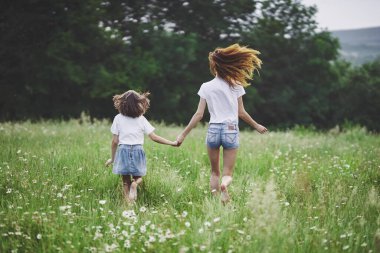 Genç anne ve kızı papatya tarlasında eğleniyorlar.