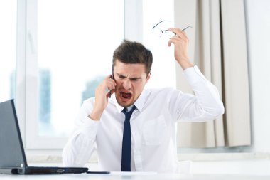 Ofiste akıllı telefondan konuşan duygusal iş adamı. 