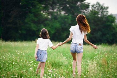 Genç anne ve kızı papatya tarlasında eğleniyorlar.