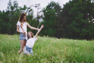 Genç anne ve kızı papatya tarlasında eğleniyorlar.