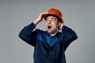 Stüdyo çekimi. Turuncu kasklı genç işçi şok oldu.